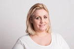 Woman with blonde hair wearing a white shirt against a light gray background