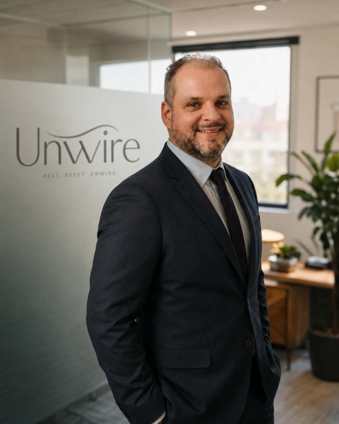 Andre Minello founder of Unwire and Ellasie in a suit standing in an office with 'Unwire' branding